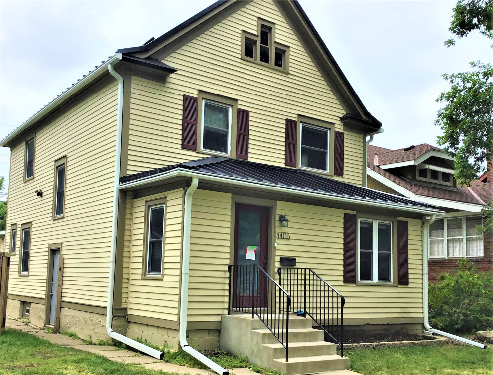Zweistöckiges Mid-Century Einfamilienhaus mit gelber Fassadenfarbe, Blechdach, braunem Dach und Verschalung in Minneapolis
