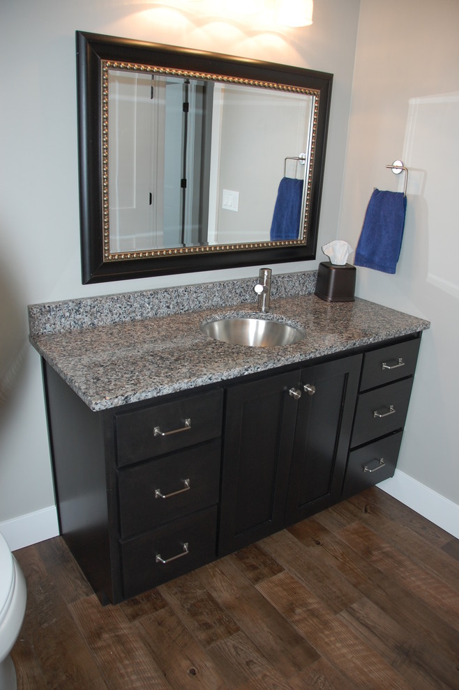 Example of a small kids' medium tone wood floor bathroom design with shaker cabinets, dark wood cabinets, gray walls, an undermount sink and granite countertops