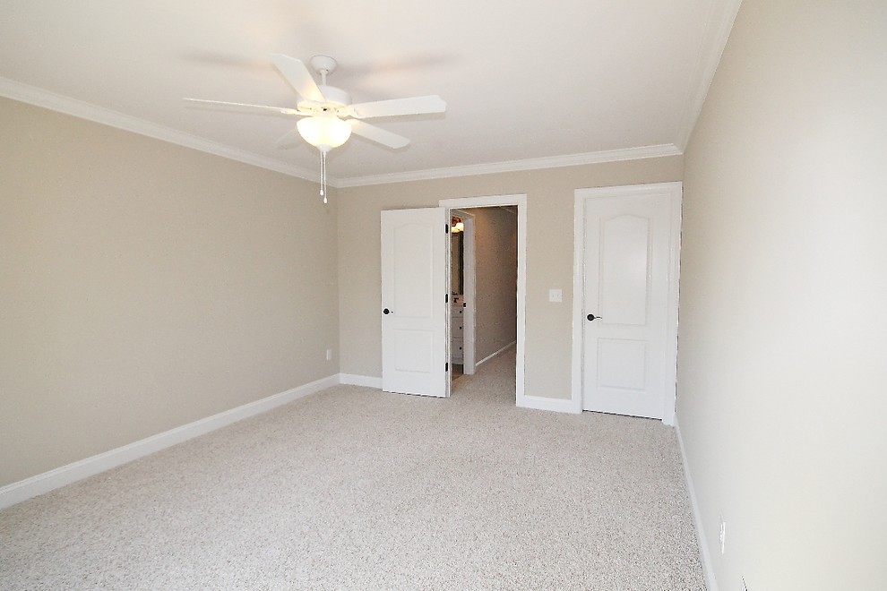 Large traditional guest bedroom in Other with beige walls and carpet.