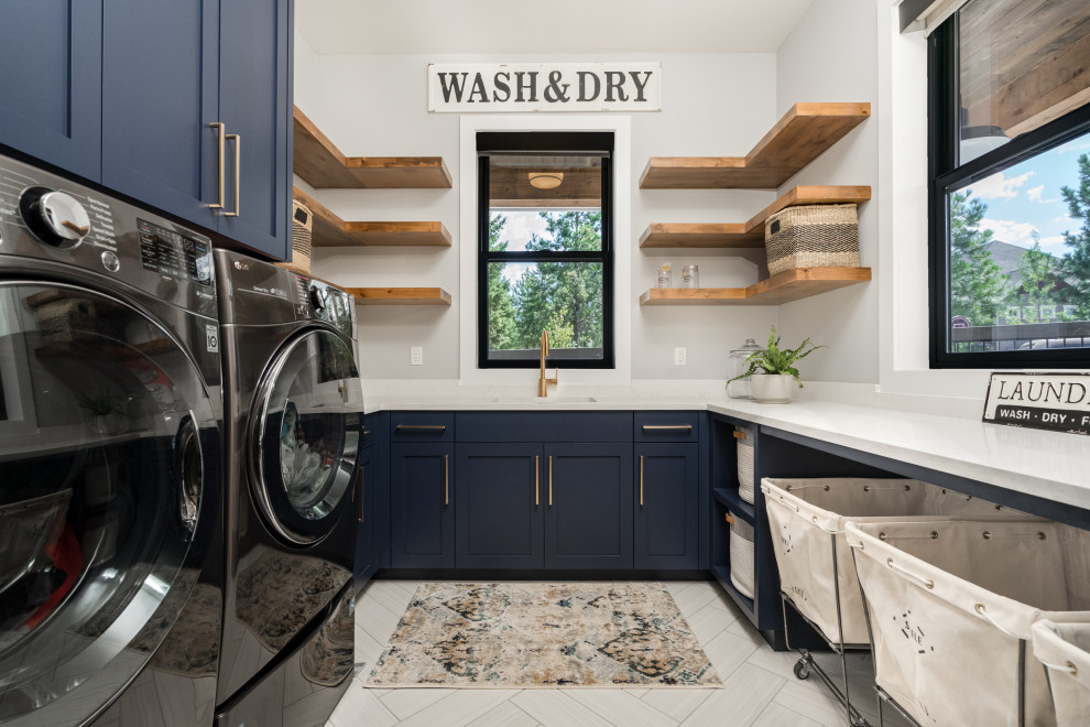 Inspiration for a country u-shaped dedicated laundry room in Seattle with an undermount sink, shaker cabinets, blue cabinets, grey walls, a side-by-side washer and dryer, beige floor and white benchtop.