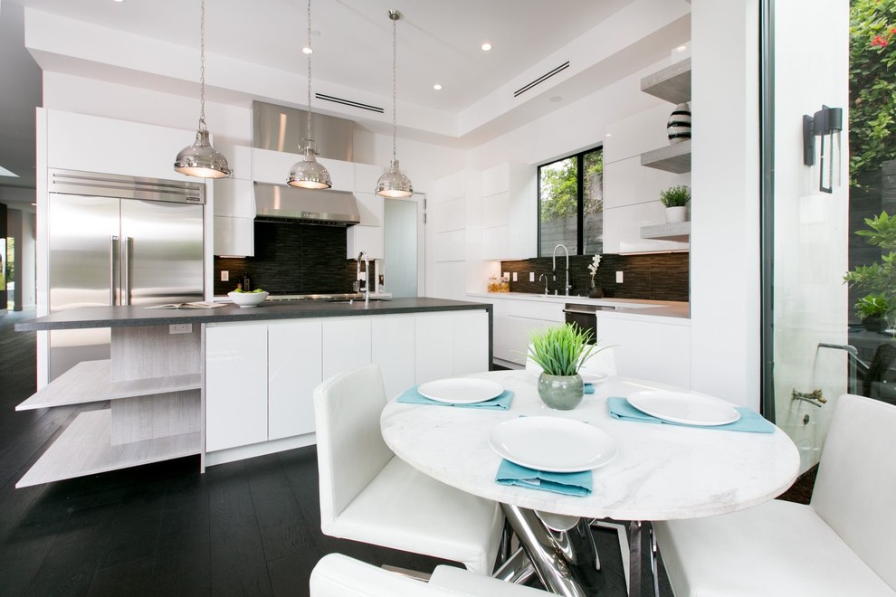 Design ideas for a mid-sized contemporary l-shaped eat-in kitchen in Los Angeles with an undermount sink, flat-panel cabinets, white cabinets, solid surface benchtops, black splashback, ceramic splashback, stainless steel appliances, dark hardwood floors and with island.