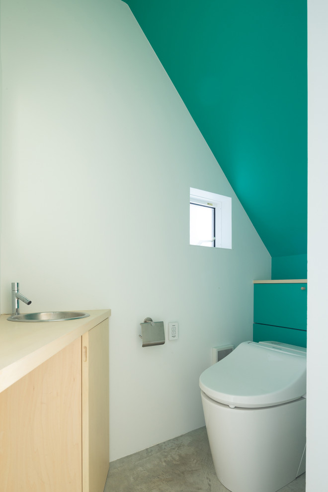 Cette photo montre un petit WC et toilettes tendance avec un placard à porte affleurante, des portes de placard beiges, WC à poser, un mur vert, sol en béton ciré, un lavabo posé, un plan de toilette en bois, un sol gris, un plan de toilette beige, meuble-lavabo encastré, un plafond en lambris de bois et du lambris de bois.