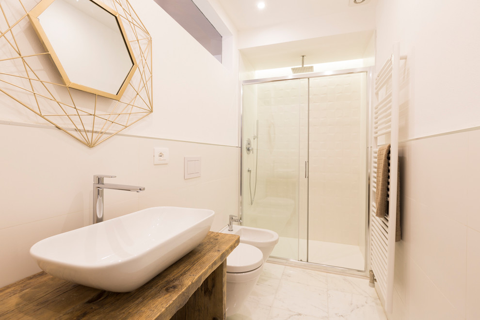 Inspiration for a mid-sized mediterranean 3/4 bathroom in Milan with open cabinets, white tile, white walls, white floor, a sliding shower screen, ceramic tile, marble floors, a vessel sink, wood benchtops, medium wood cabinets, an alcove shower, a wall-mount toilet and brown benchtops.