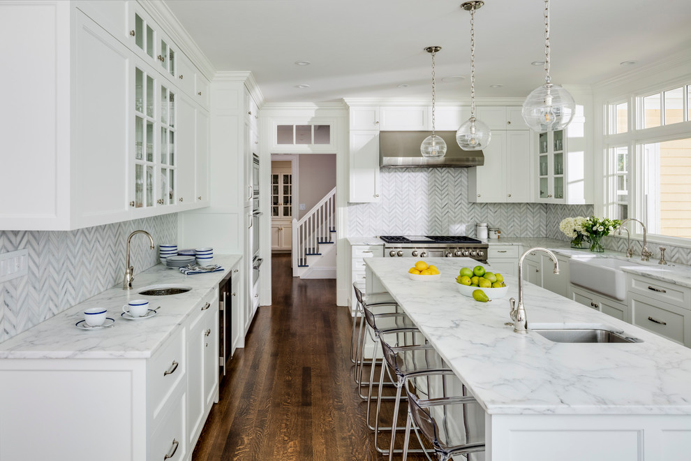 Design ideas for a mid-sized transitional u-shaped kitchen in Boston with recessed-panel cabinets, white cabinets, marble benchtops, with island, brown floor, a farmhouse sink, white splashback, marble splashback, stainless steel appliances and dark hardwood floors.
