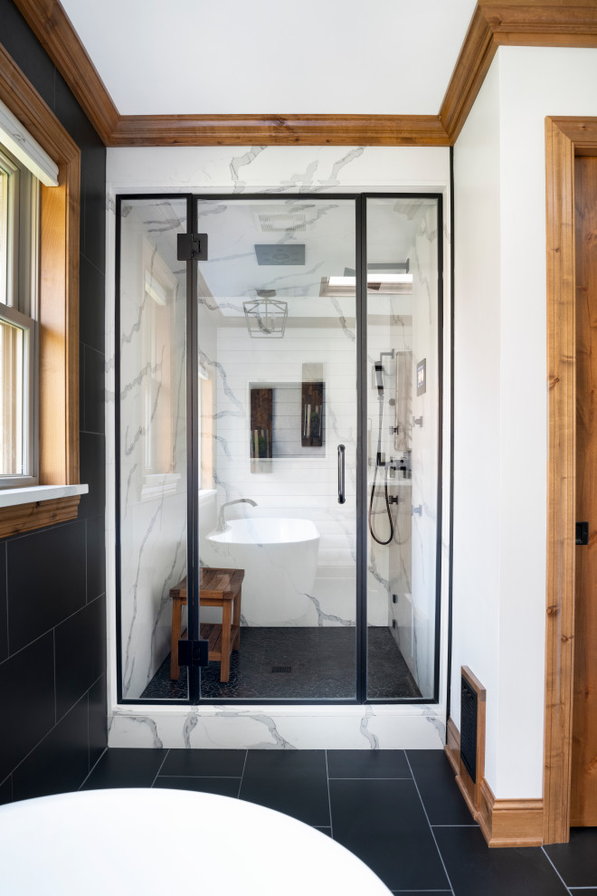 Inspiration for a large country master bathroom in Minneapolis with a freestanding tub, black and white tile, an alcove shower, pebble tile floors, black floor and a hinged shower door.
