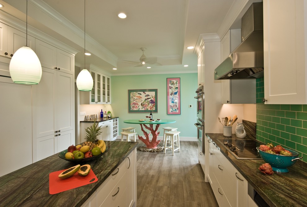 Inspiration for a tropical kitchen in Hawaii with shaker cabinets, white cabinets, granite benchtops, green splashback, glass tile splashback, panelled appliances, vinyl floors and with island.