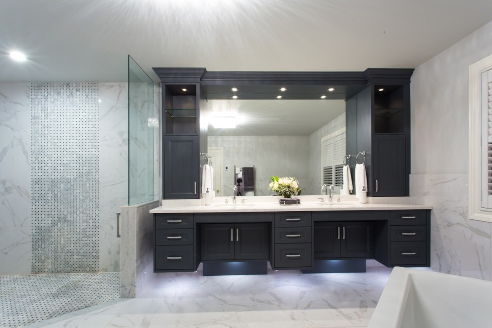 Large transitional master bathroom in Toronto with shaker cabinets, blue cabinets, a freestanding tub, a curbless shower, a one-piece toilet, gray tile, white tile, stone tile, white walls, marble floors, an undermount sink and solid surface benchtops.