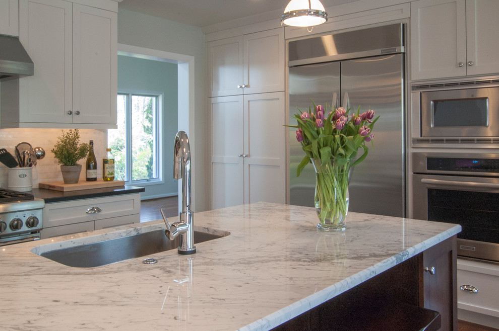 This is an example of a large transitional l-shaped eat-in kitchen in Philadelphia with an undermount sink, shaker cabinets, white cabinets, granite benchtops, white splashback, stone tile splashback, stainless steel appliances, medium hardwood floors and with island.