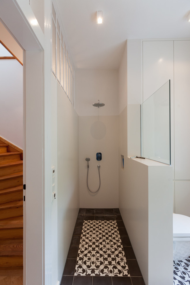 Photo of a mid-sized eclectic bathroom in Frankfurt with a curbless shower, white walls, porcelain floors, a wall-mount toilet and ceramic tile.