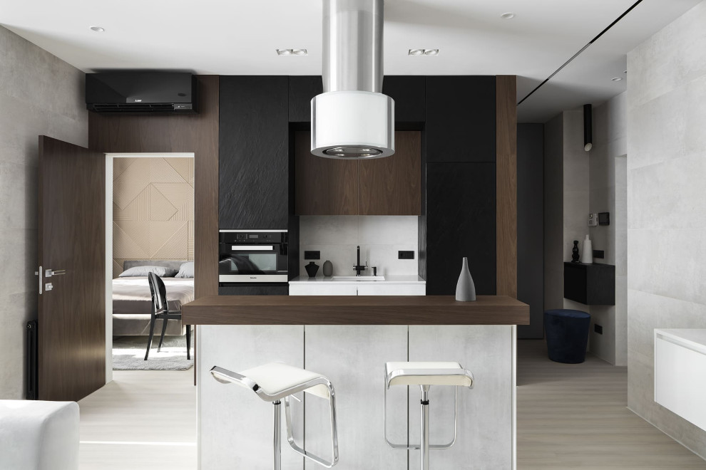 Inspiration for a mid-sized contemporary single-wall open plan kitchen in Moscow with an undermount sink, flat-panel cabinets, black cabinets, quartz benchtops, grey splashback, porcelain splashback, black appliances, light hardwood floors, with island, beige floor and white benchtop.