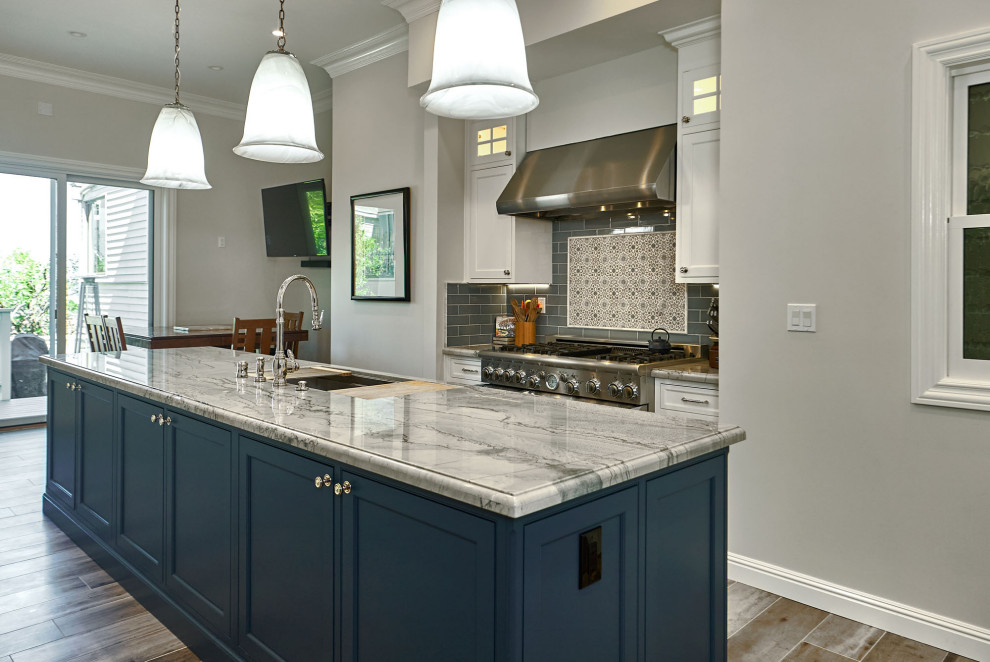 Bild på ett stort vintage blå blått kök, med en trippel diskho, luckor med profilerade fronter, vita skåp, bänkskiva i kvartsit, blått stänkskydd, stänkskydd i keramik, integrerade vitvaror, klinkergolv i porslin, en köksö och grått golv