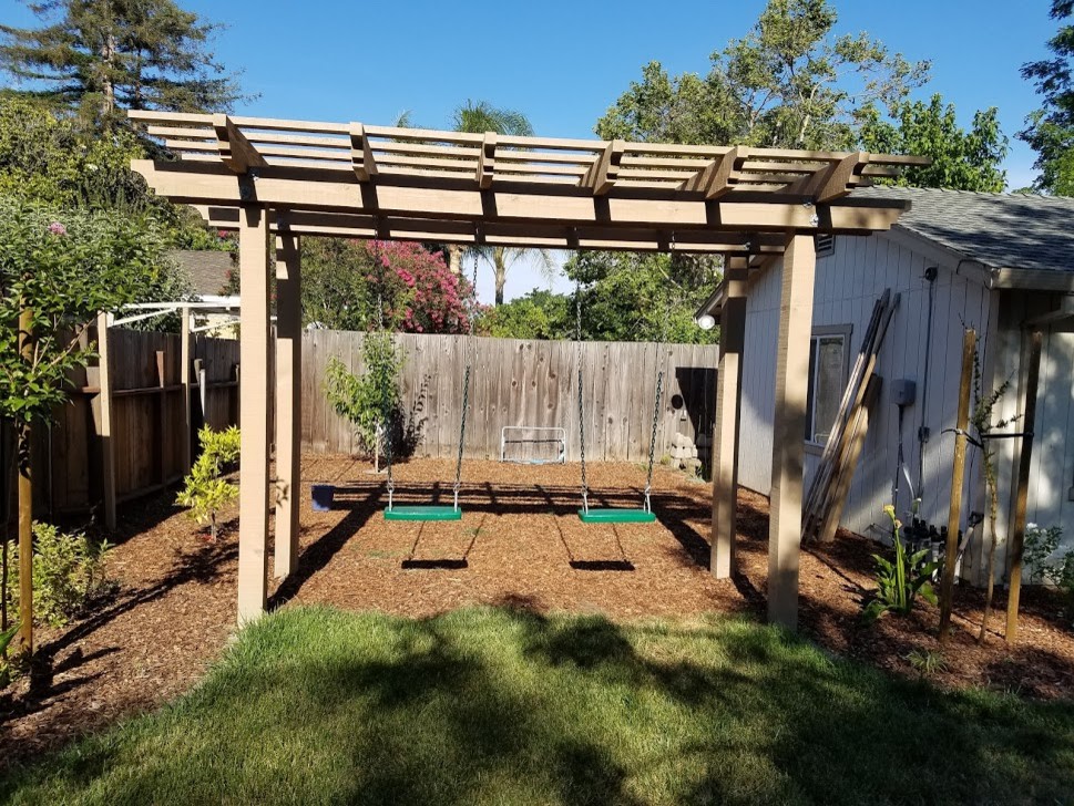 Inspiration for a mid-sized traditional partial sun backyard outdoor playset in Orange County with a pergola.
