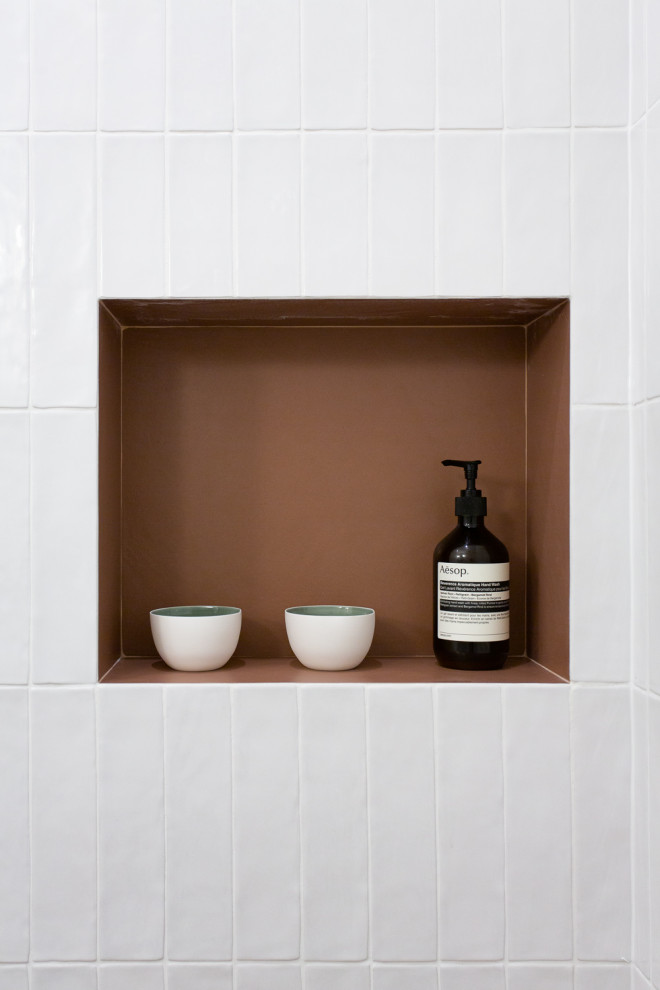Klassisk inredning av ett litet vit vitt badrum med dusch, med luckor med infälld panel, skåp i ljust trä, en kantlös dusch, vit kakel, porslinskakel, rosa väggar, klinkergolv i keramik, ett konsol handfat, bänkskiva i akrylsten, orange golv och med dusch som är öppen