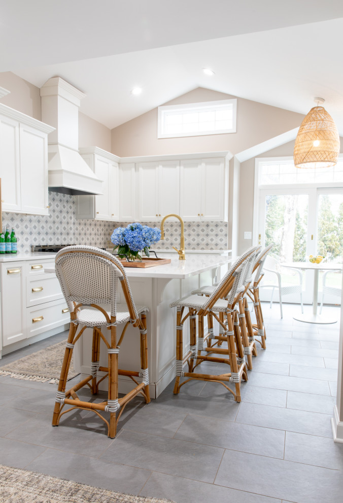 Mid-sized transitional l-shaped open plan kitchen in New York with a farmhouse sink, shaker cabinets, white cabinets, quartz benchtops, white splashback, mosaic tile splashback, stainless steel appliances, ceramic floors, with island, grey floor, white benchtop and vaulted.