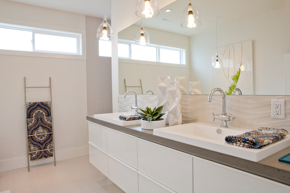 Photo of a mid-sized contemporary master bathroom in Vancouver with white cabinets, concrete benchtops, a double shower, a one-piece toilet, porcelain tile, white walls, porcelain floors, a drop-in sink, flat-panel cabinets, beige tile and grey benchtops.