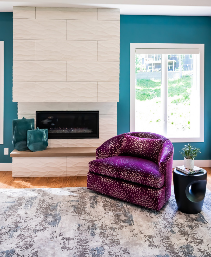 シーダーラピッズにある高級な中くらいなモダンスタイルのおしゃれなリビング (青い壁、無垢フローリング、標準型暖炉、壁掛け型テレビ、タイルの暖炉まわり、茶色い床) の写真