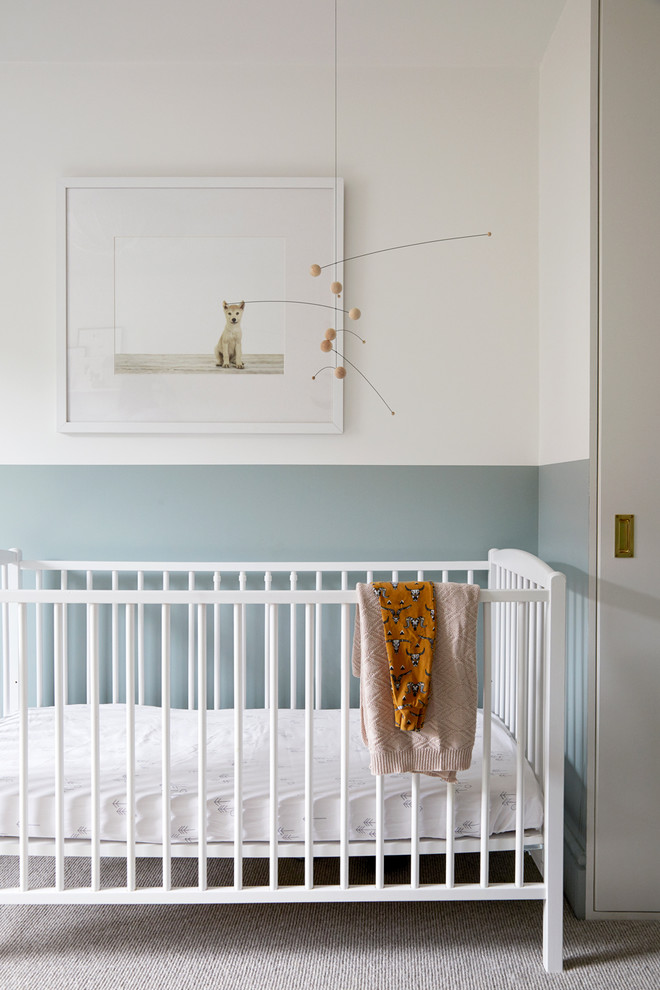 This is an example of a mid-sized scandinavian gender-neutral nursery in London with blue walls, carpet and beige floor.