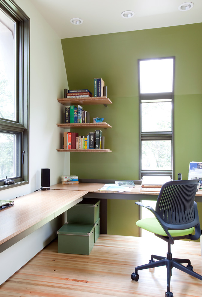 Inspiration for a modern home office in Nashville with green walls, medium hardwood floors, a built-in desk and beige floor.