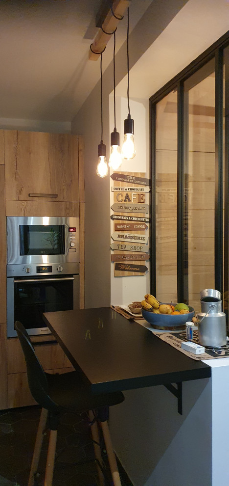 This is an example of a medium sized industrial l-shaped open plan kitchen in Paris with a submerged sink, shaker cabinets, light wood cabinets, laminate countertops, stainless steel appliances, cement flooring, no island, grey floors and black worktops.