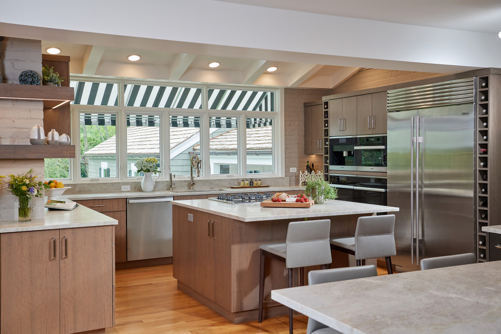 Example of a large trendy u-shaped medium tone wood floor eat-in kitchen design in Chicago with a farmhouse sink, quartz countertops, beige backsplash, stone slab backsplash, stainless steel appliances, an island and beige countertops