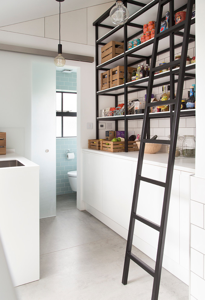 Small contemporary galley kitchen pantry in London with flat-panel cabinets, white cabinets, white splashback, subway tile splashback, solid surface benchtops, concrete floors and no island.
