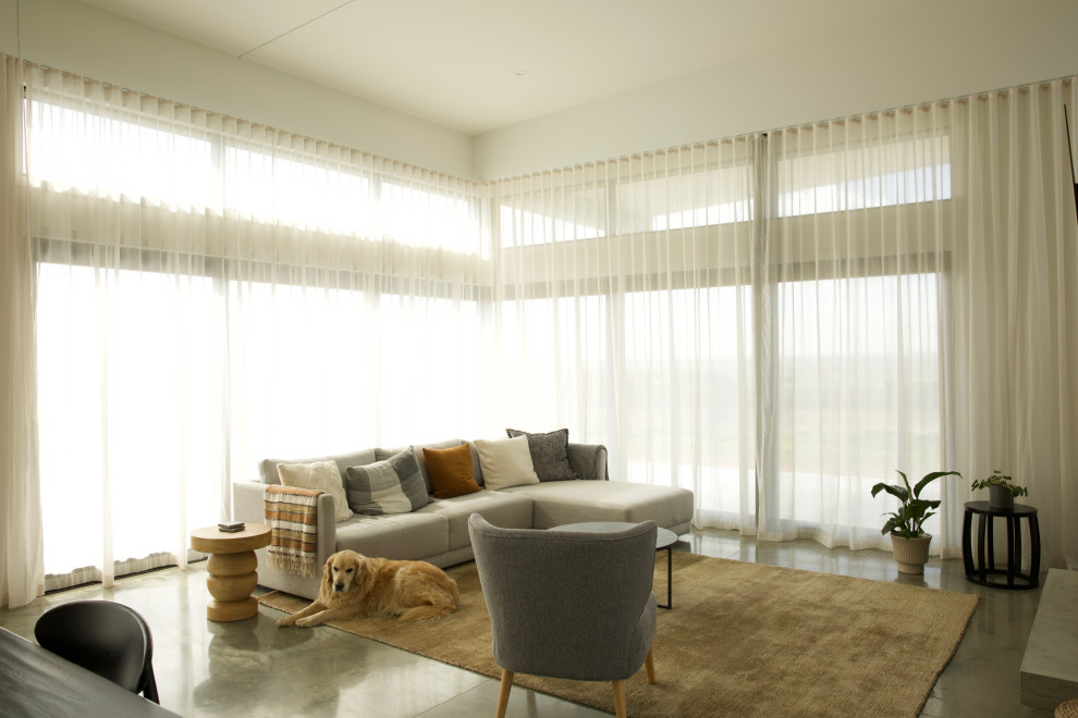 Großes, Offenes Modernes Wohnzimmer mit weißer Wandfarbe, Betonboden, Kaminumrandung aus Beton, TV-Wand, grauem Boden und gewölbter Decke in Sonstige