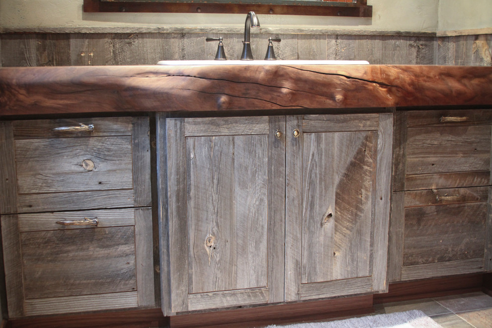 Bathroom - small rustic 3/4 brown tile bathroom idea with distressed cabinets, wood countertops, beige walls and a drop-in sink