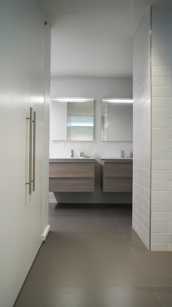 This is an example of a mid-sized modern master bathroom in New York with flat-panel cabinets, light wood cabinets, white tile, white walls, porcelain floors, an integrated sink, ceramic tile, solid surface benchtops, white benchtops, a wall-mount toilet, an alcove tub and an open shower.