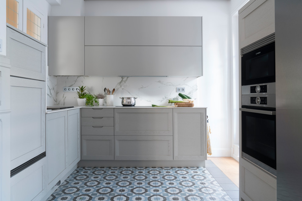 Photo of a transitional kitchen in Other with a double-bowl sink, grey cabinets, white splashback, stainless steel appliances, ceramic floors, blue floor and white benchtop.