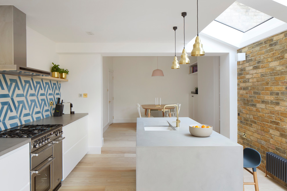 Photo of a mid-sized contemporary single-wall kitchen in London with an undermount sink, flat-panel cabinets, white cabinets, blue splashback, ceramic splashback, light hardwood floors, with island and beige floor.