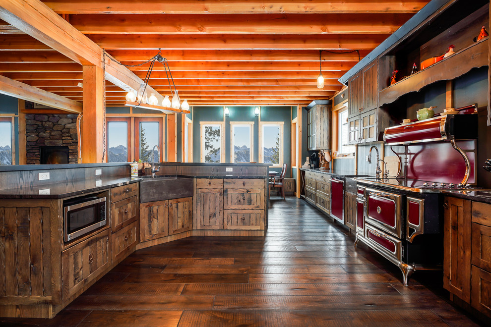 Eat-in kitchen - large rustic galley eat-in kitchen idea with a farmhouse sink, recessed-panel cabinets, brown cabinets, quartzite countertops, colored appliances and an island
