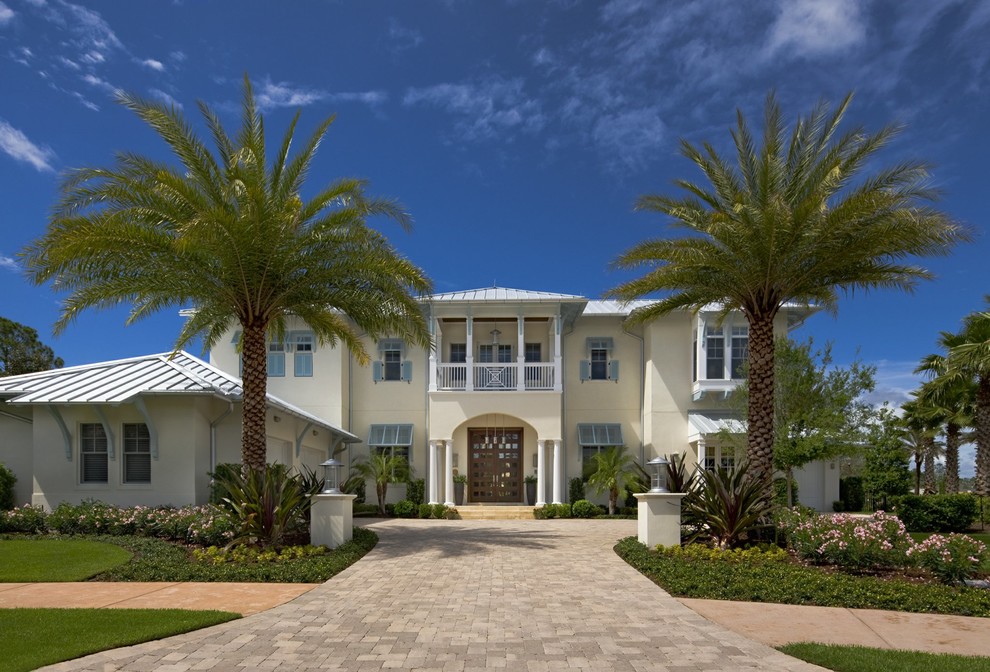 Design ideas for an expansive tropical two-storey stucco beige exterior in Orlando with a hip roof.