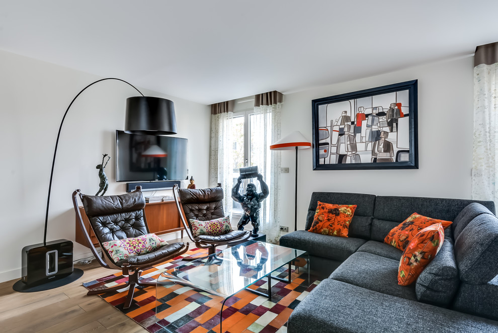 Cette image montre un salon bohème avec une salle de réception, un mur blanc, parquet clair et un téléviseur fixé au mur.