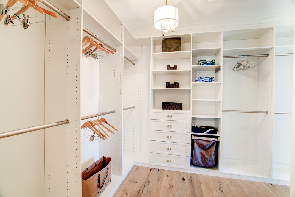 Expansive country gender-neutral walk-in wardrobe in Richmond with recessed-panel cabinets, white cabinets, light hardwood floors and brown floor.