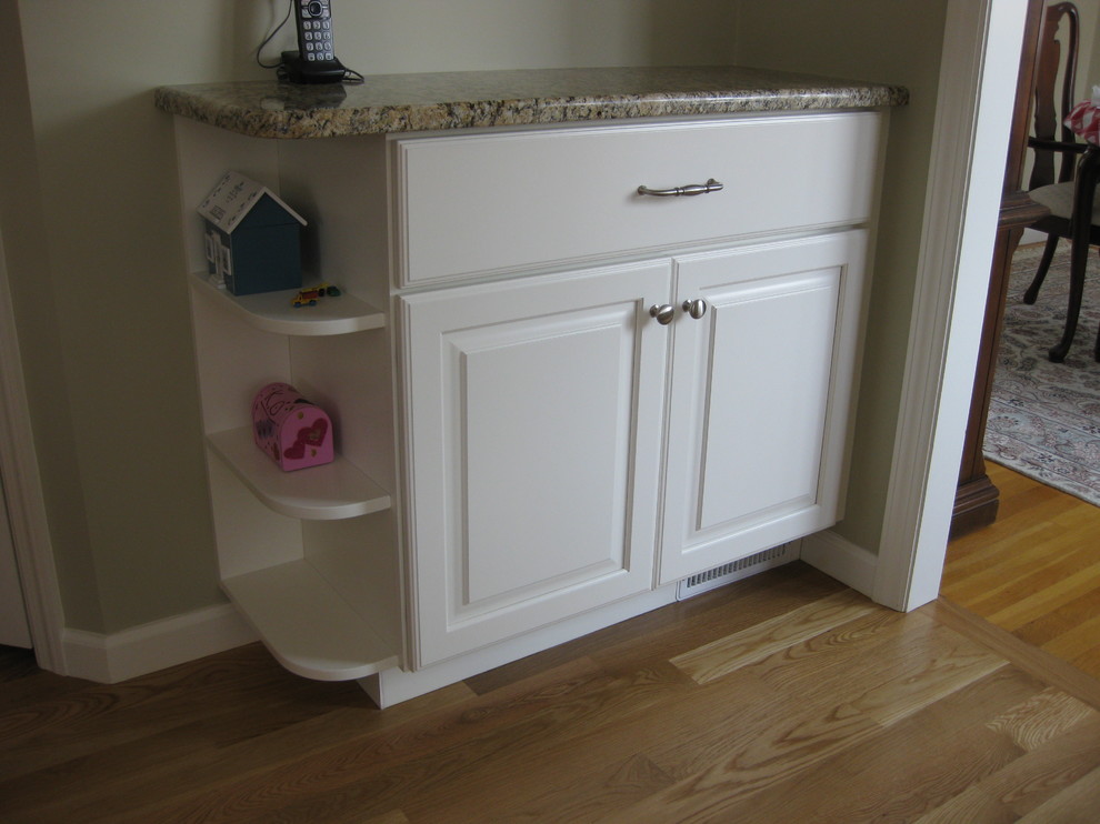 Transitional u-shaped medium tone wood floor eat-in kitchen photo in Boston with an undermount sink, raised-panel cabinets, white cabinets, granite countertops, white backsplash, ceramic backsplash, stainless steel appliances, an island and beige countertops