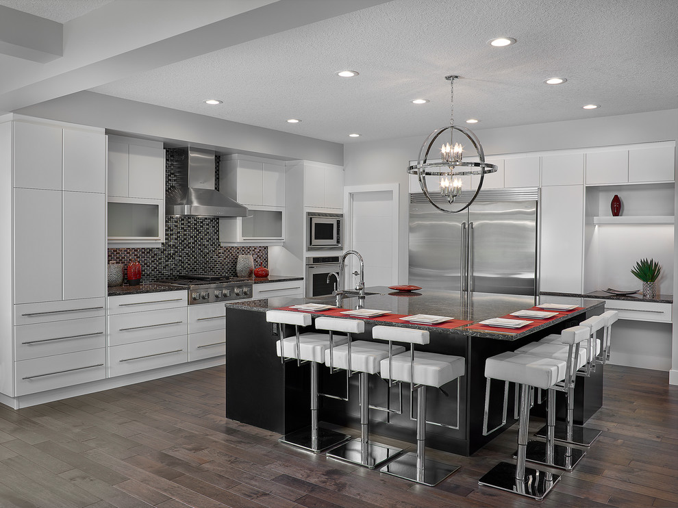 Inspiration for a mid-sized transitional dark wood floor kitchen remodel in Edmonton with a farmhouse sink, flat-panel cabinets, white cabinets, quartzite countertops, black backsplash, mosaic tile backsplash, stainless steel appliances and an island