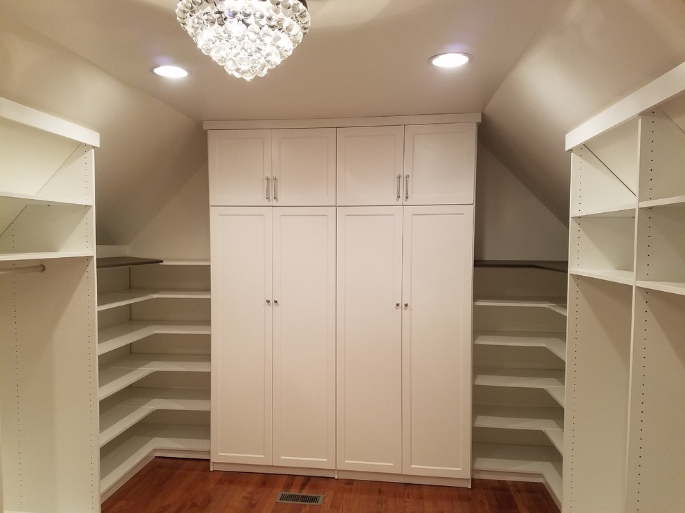 This is an example of a mid-sized walk-in wardrobe in Chicago with shaker cabinets, white cabinets, medium hardwood floors and brown floor.