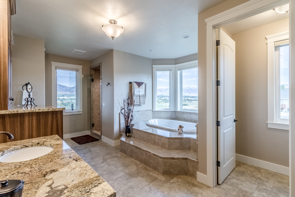 Photo of a mid-sized country master bathroom in Salt Lake City with beaded inset cabinets, medium wood cabinets, a drop-in tub, a corner shower, a one-piece toilet, beige tile, marble, beige walls, cement tiles, a drop-in sink and granite benchtops.