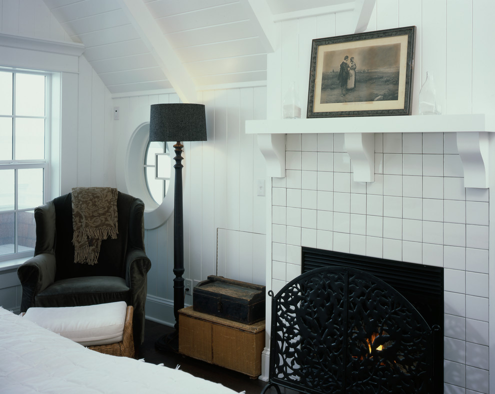 This is an example of a mid-sized beach style guest bedroom in Seattle with white walls, dark hardwood floors, a standard fireplace and a tile fireplace surround.