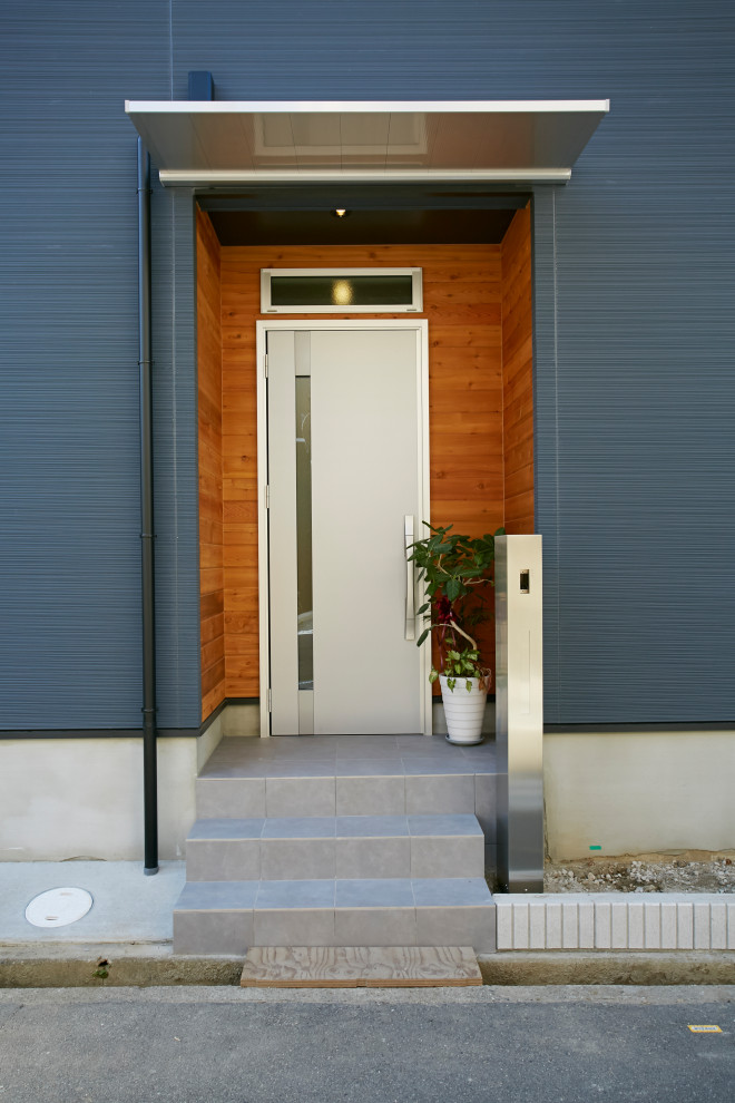 Cette photo montre une porte d'entrée de taille moyenne avec un mur bleu, une porte simple et une porte métallisée.