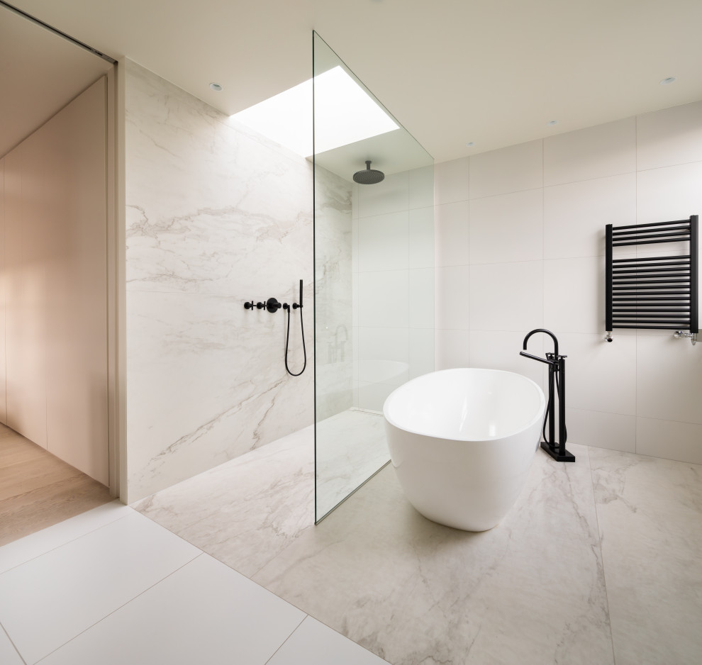 Design ideas for a large contemporary ensuite bathroom in London with flat-panel cabinets, white cabinets, a freestanding bath, a walk-in shower, black and white tiles, marble tiles, solid surface worktops, white worktops, double sinks and a floating vanity unit.