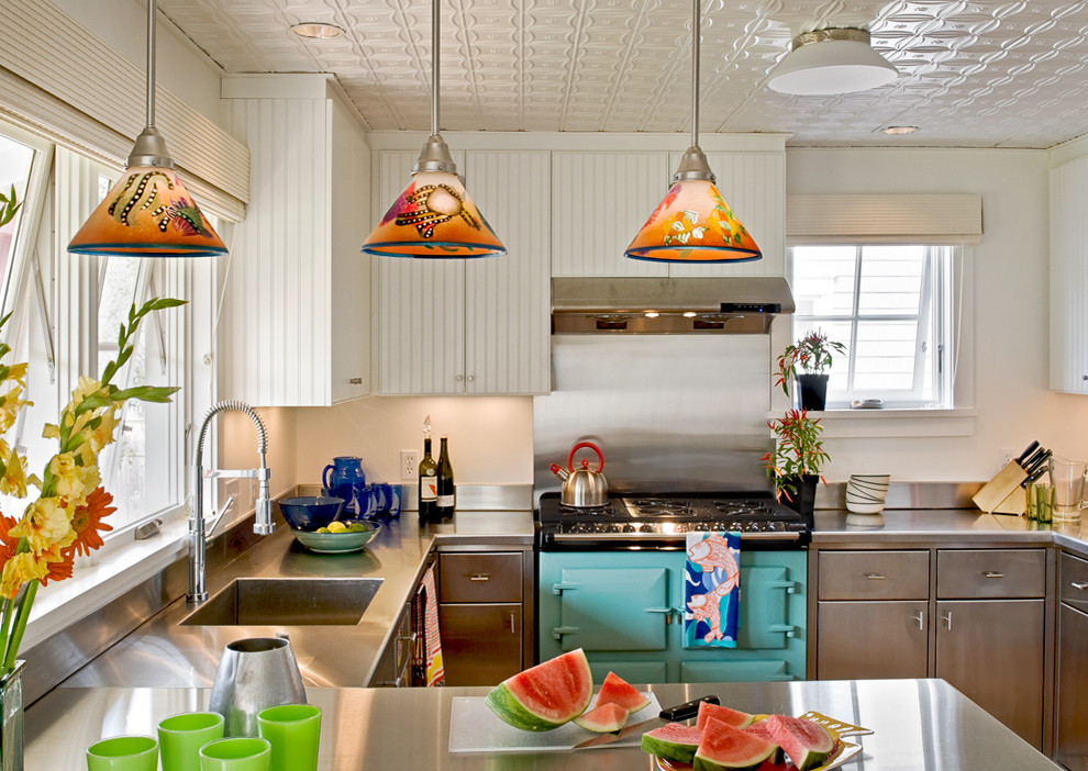 Inspiration for a beach style kitchen in Portland Maine with an integrated sink, stainless steel cabinets, stainless steel benchtops, coloured appliances, flat-panel cabinets, metallic splashback and metal splashback.