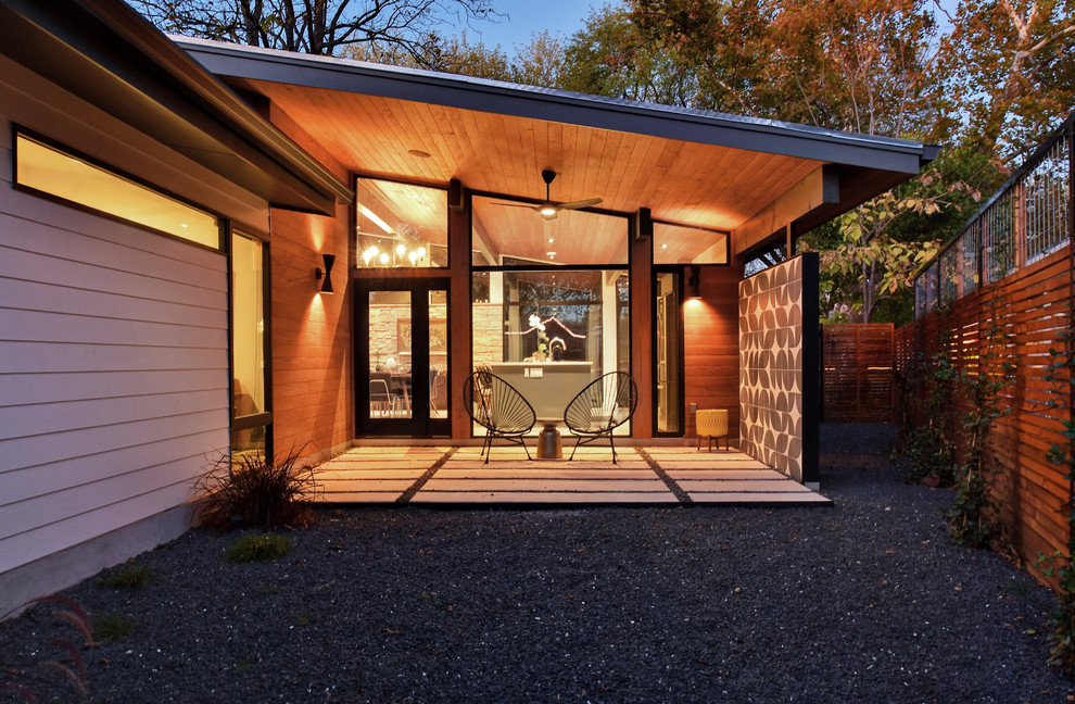 This is an example of a midcentury backyard patio in Austin with a roof extension.