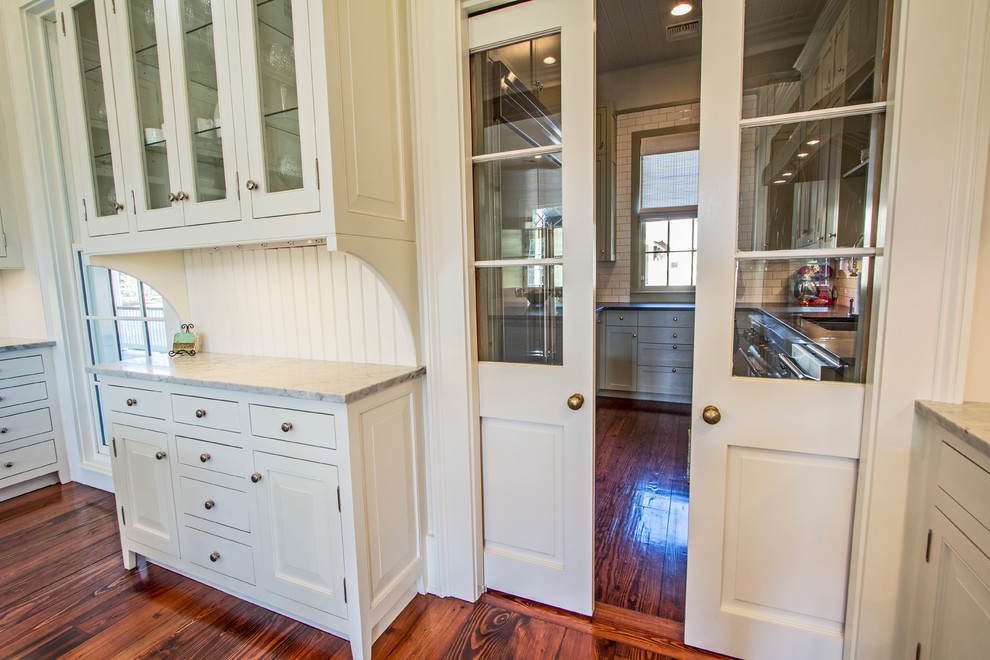Inspiration for a mid-sized traditional galley eat-in kitchen in New Orleans with beaded inset cabinets, white cabinets, marble benchtops, white splashback, subway tile splashback, stainless steel appliances, medium hardwood floors and no island.