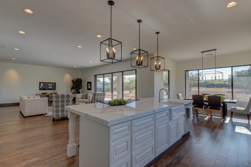 Mid-sized transitional l-shaped dark wood floor and brown floor eat-in kitchen photo in Phoenix with a farmhouse sink, raised-panel cabinets, white cabinets, marble countertops, white backsplash, subway tile backsplash, stainless steel appliances and an island