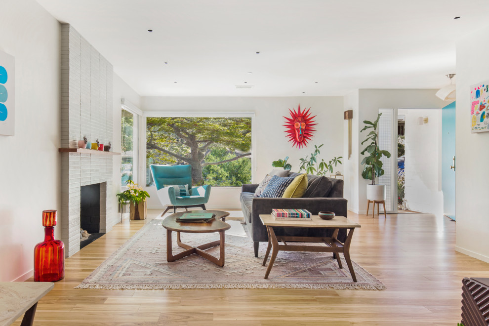Midcentury living room in San Francisco with white walls, light hardwood floors, a standard fireplace, a brick fireplace surround and brown floor.