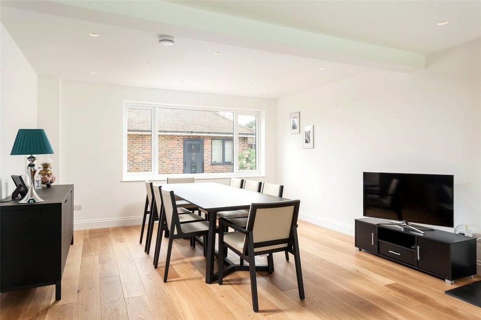 This is an example of a contemporary open plan dining in Sussex with medium hardwood floors.