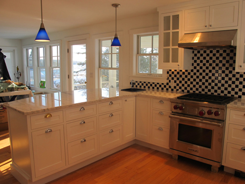 Photo of a mid-sized eclectic u-shaped eat-in kitchen in Portland Maine with a drop-in sink, shaker cabinets, white cabinets, marble benchtops, multi-coloured splashback, ceramic splashback, stainless steel appliances, medium hardwood floors and a peninsula.