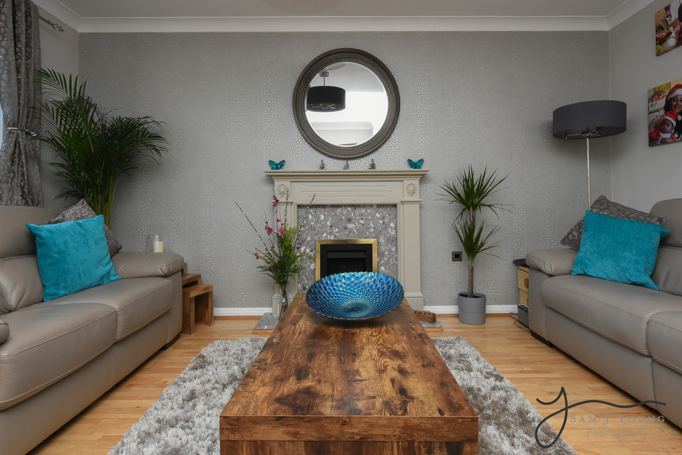 This is an example of a small modern enclosed living room in Buckinghamshire with laminate floors, a standard fireplace, a wood fireplace surround and brown floor.