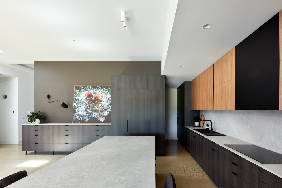 Large contemporary galley eat-in kitchen in Adelaide with an integrated sink, black cabinets, grey splashback, concrete floors, with island and grey benchtop.